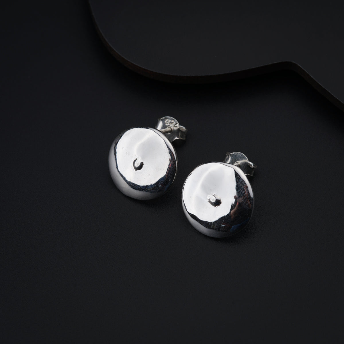 a pair of silver earrings sitting on top of a black surface