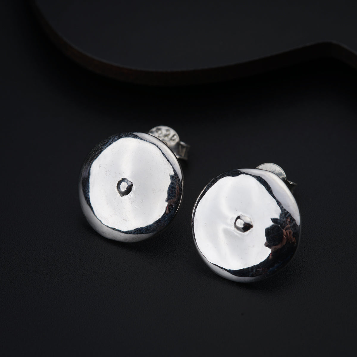 a pair of silver earrings sitting on top of a black surface