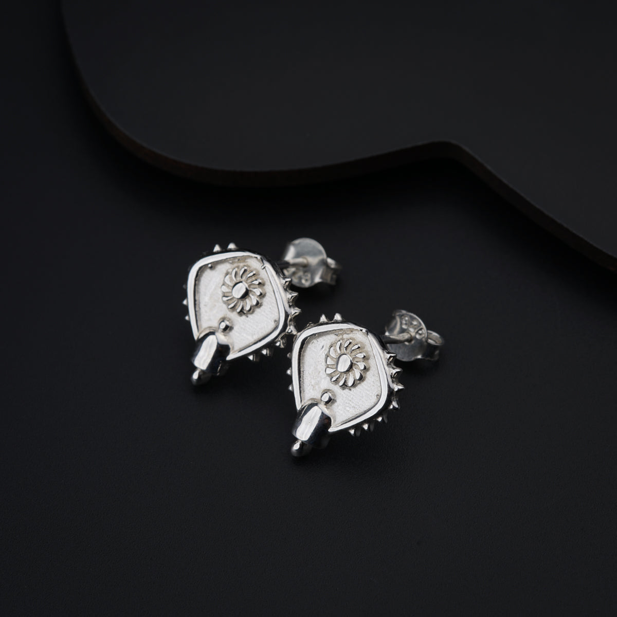 a pair of earrings on a black surface