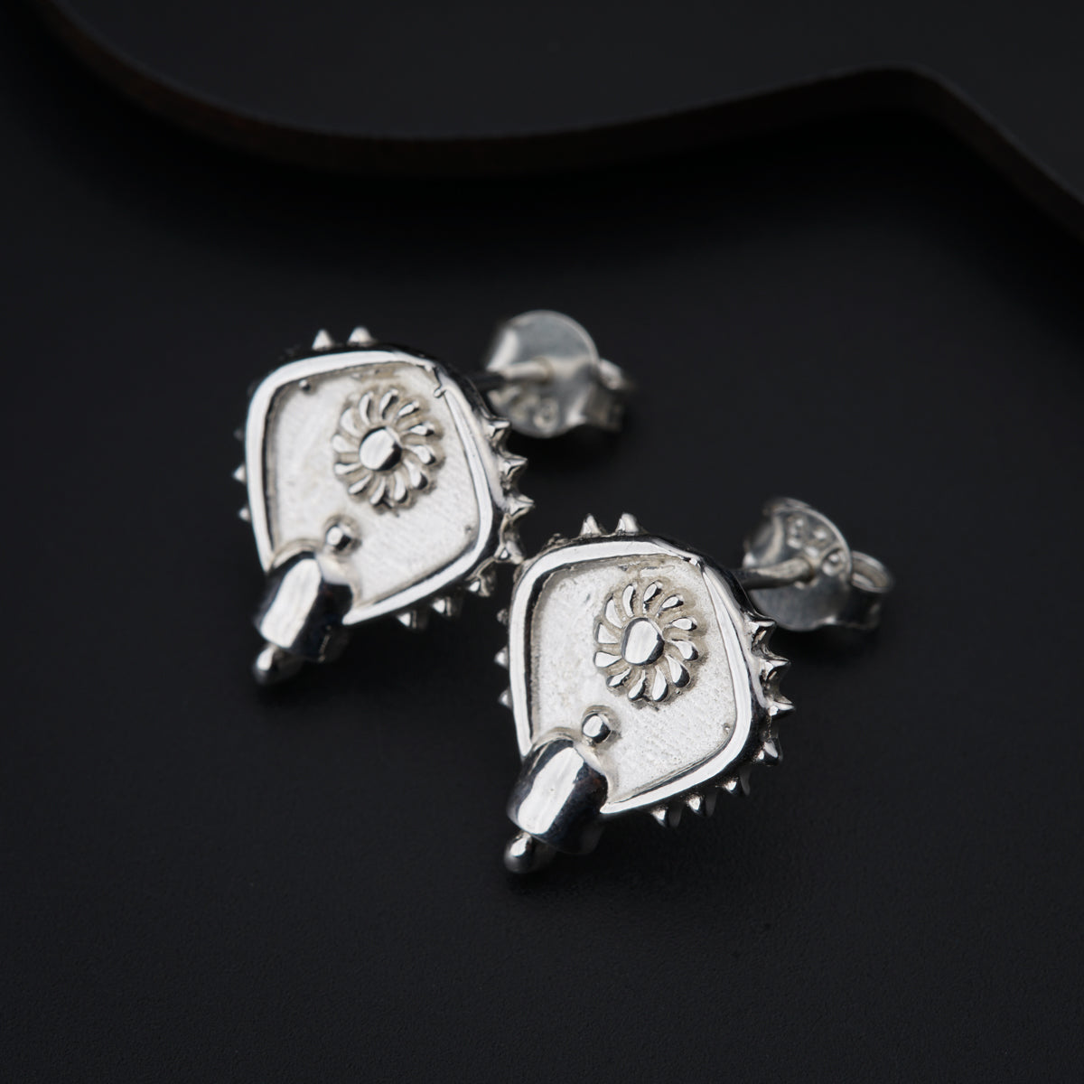 a pair of silver earrings on a black surface