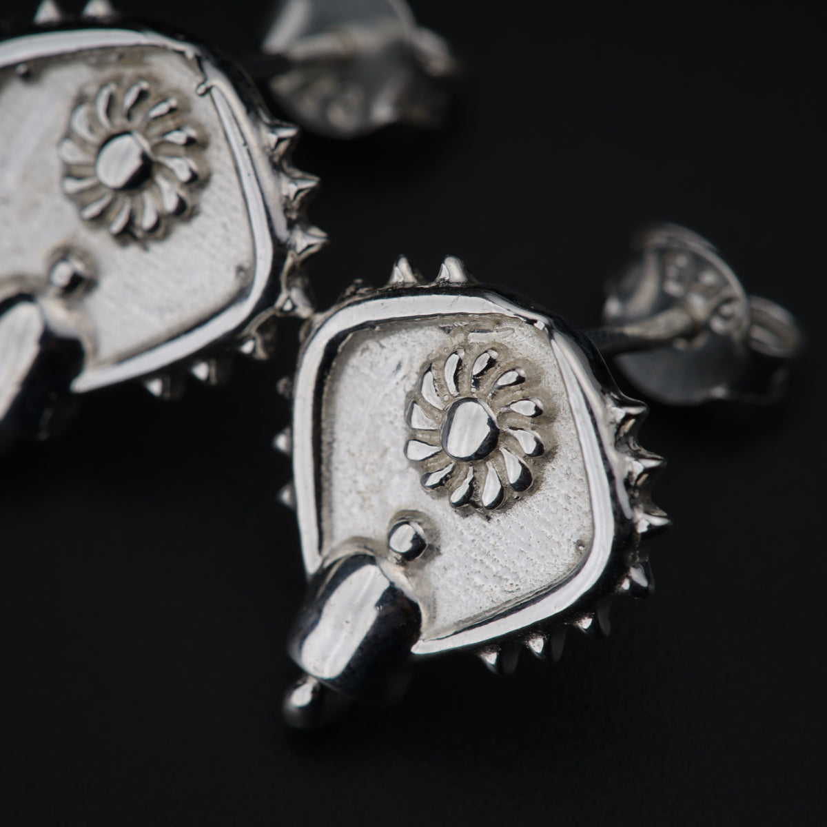 a close up of a pair of earrings on a black surface