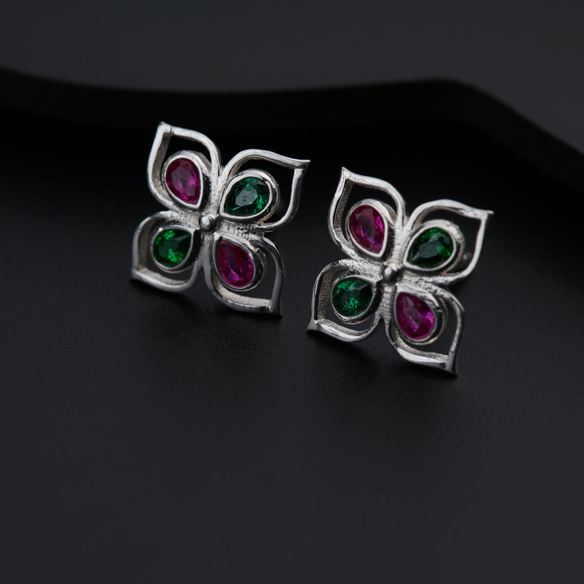 a pair of earrings with green and red stones