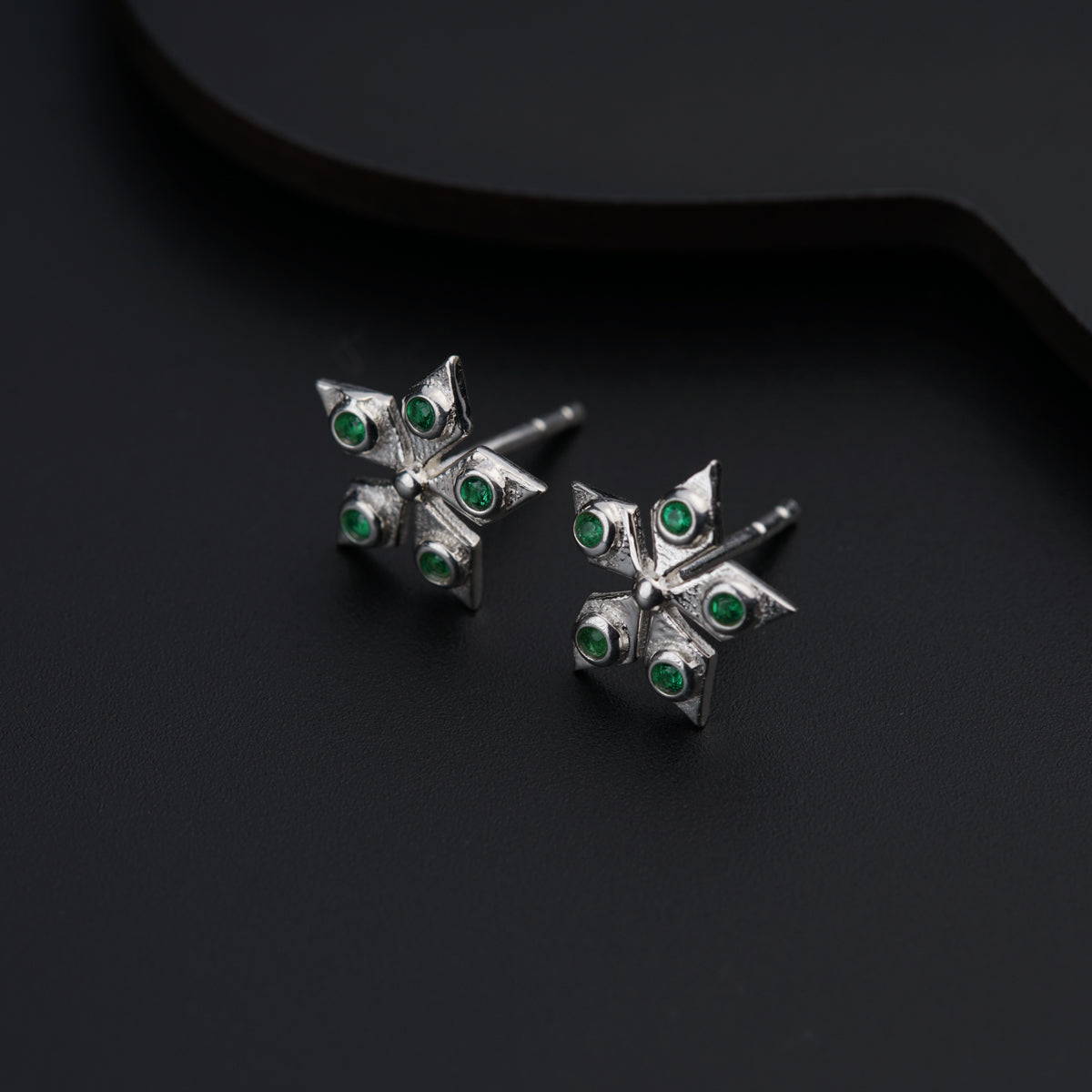 a pair of silver earrings with green stones