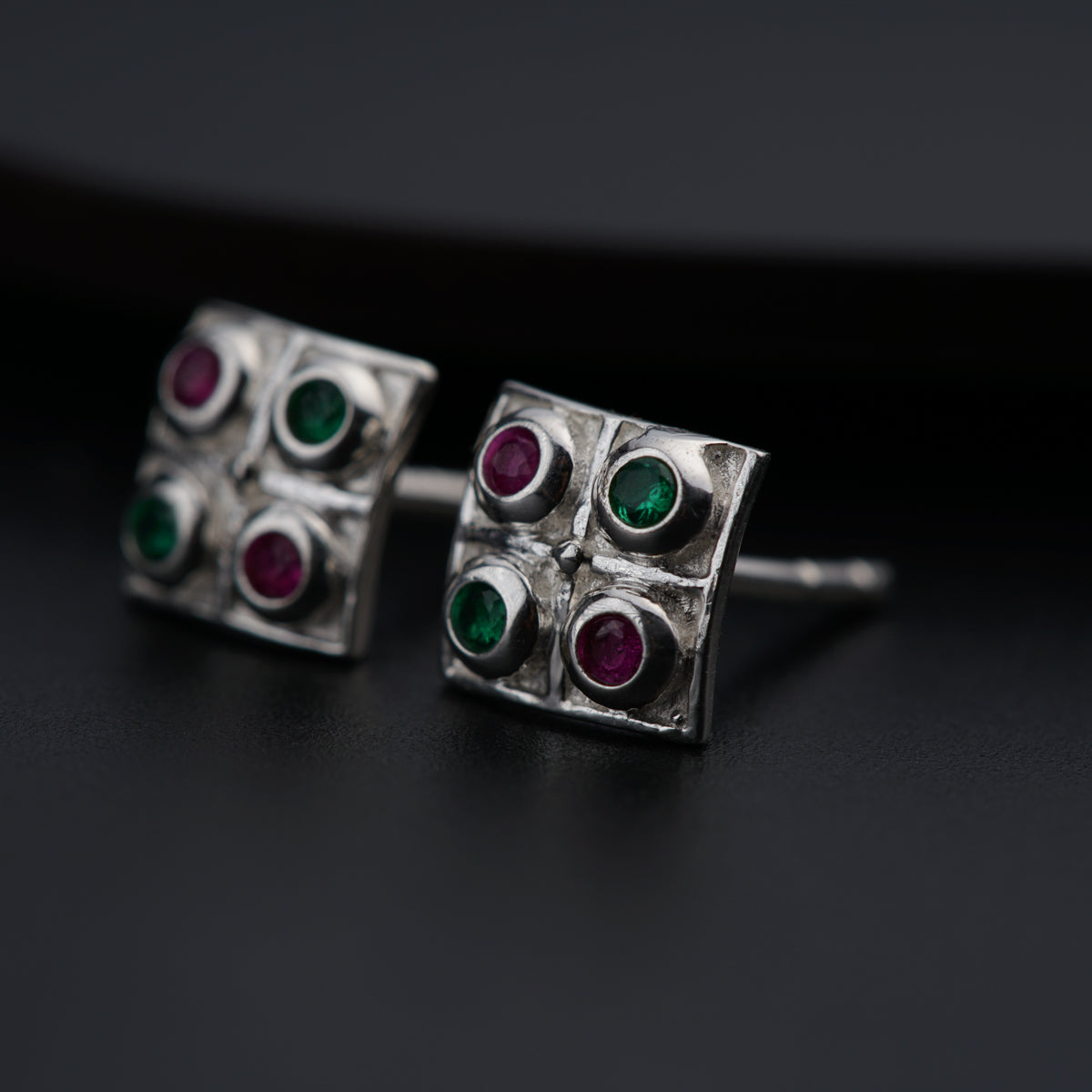 a pair of silver cufflinks with colored stones