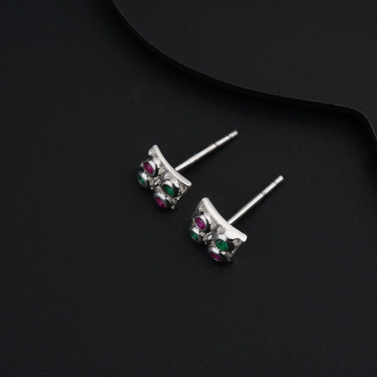 a pair of silver earrings with green and pink stones