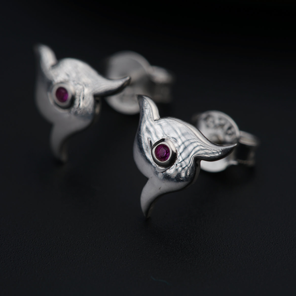 a pair of silver earrings with red stones