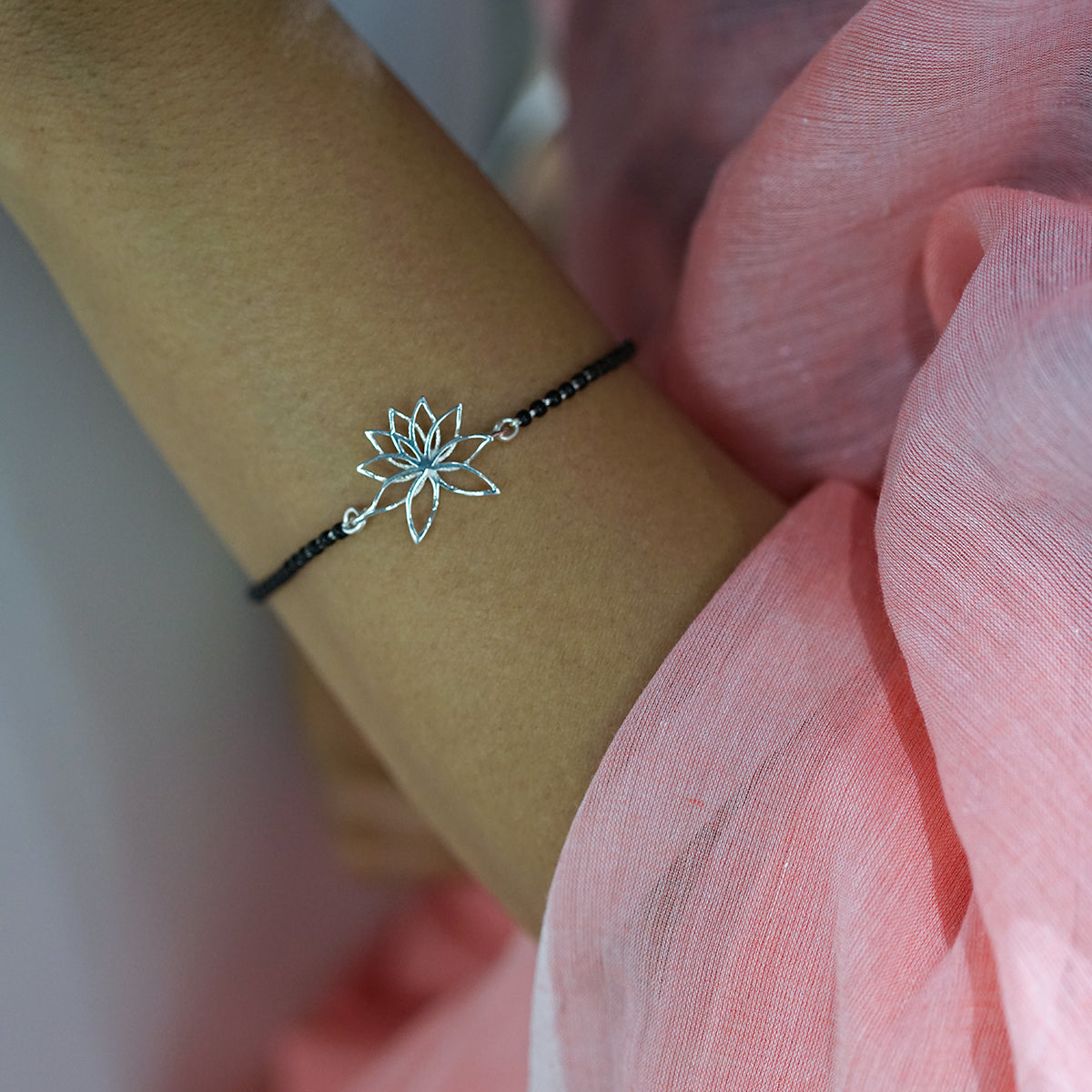 a woman wearing a bracelet with a flower on it