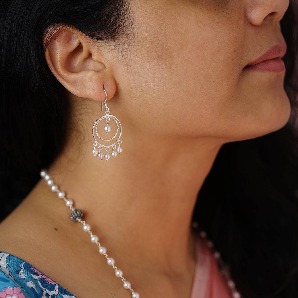 a close up of a woman wearing a necklace and earrings