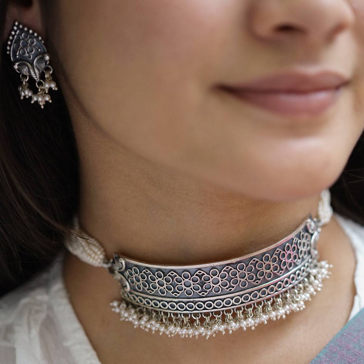 a close up of a woman wearing a necklace and earrings