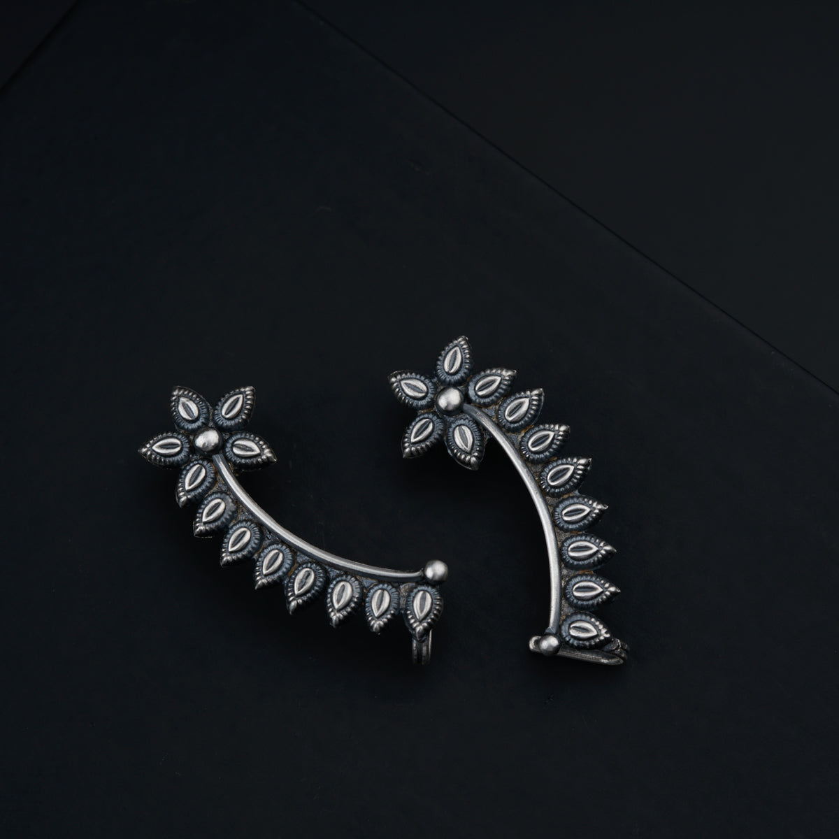 a close up of a pair of earrings on a black surface