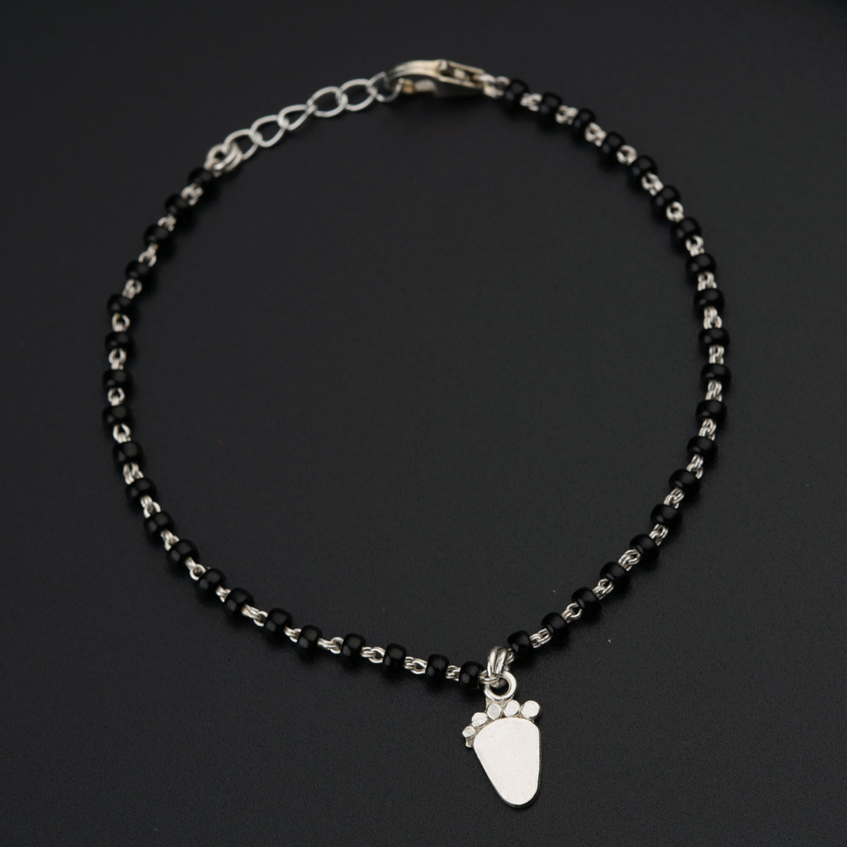 a black beaded bracelet with a silver charm