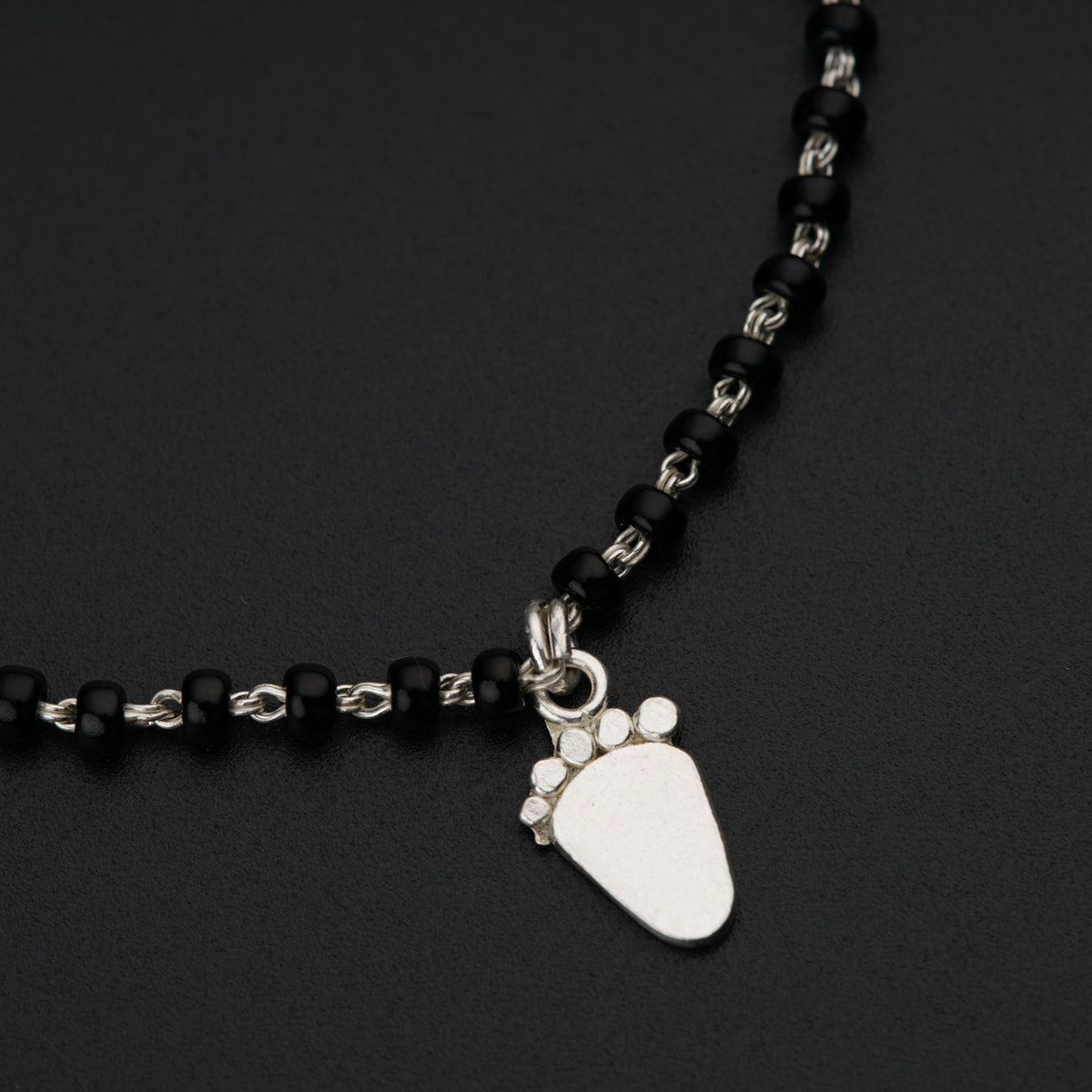 a black beaded necklace with a dog paw charm