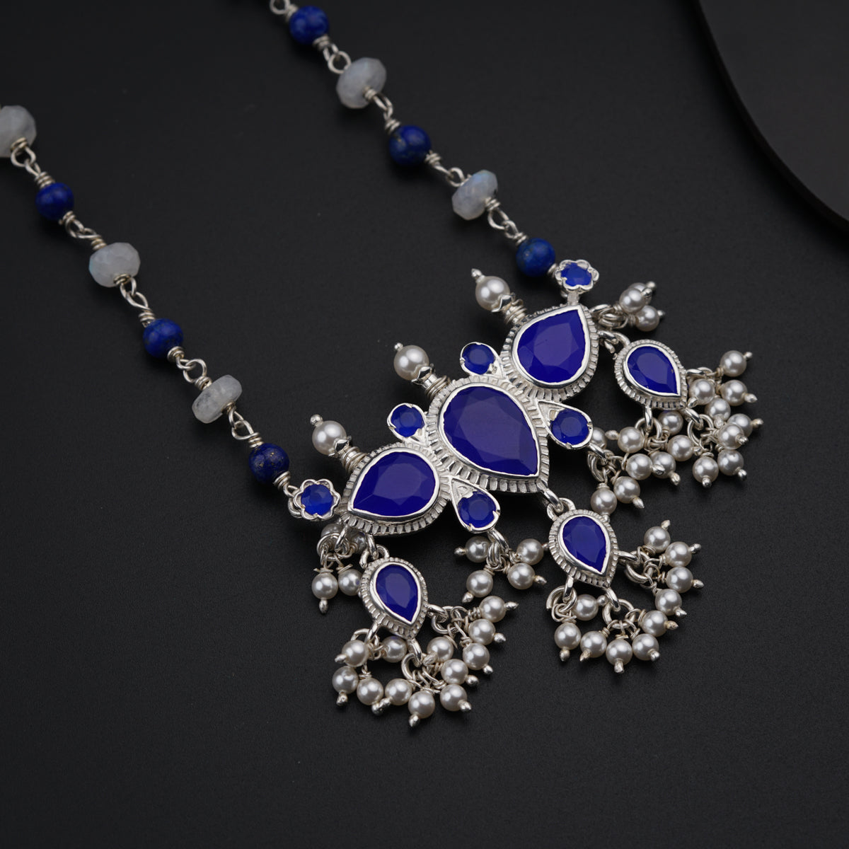 a blue and white necklace on a black surface