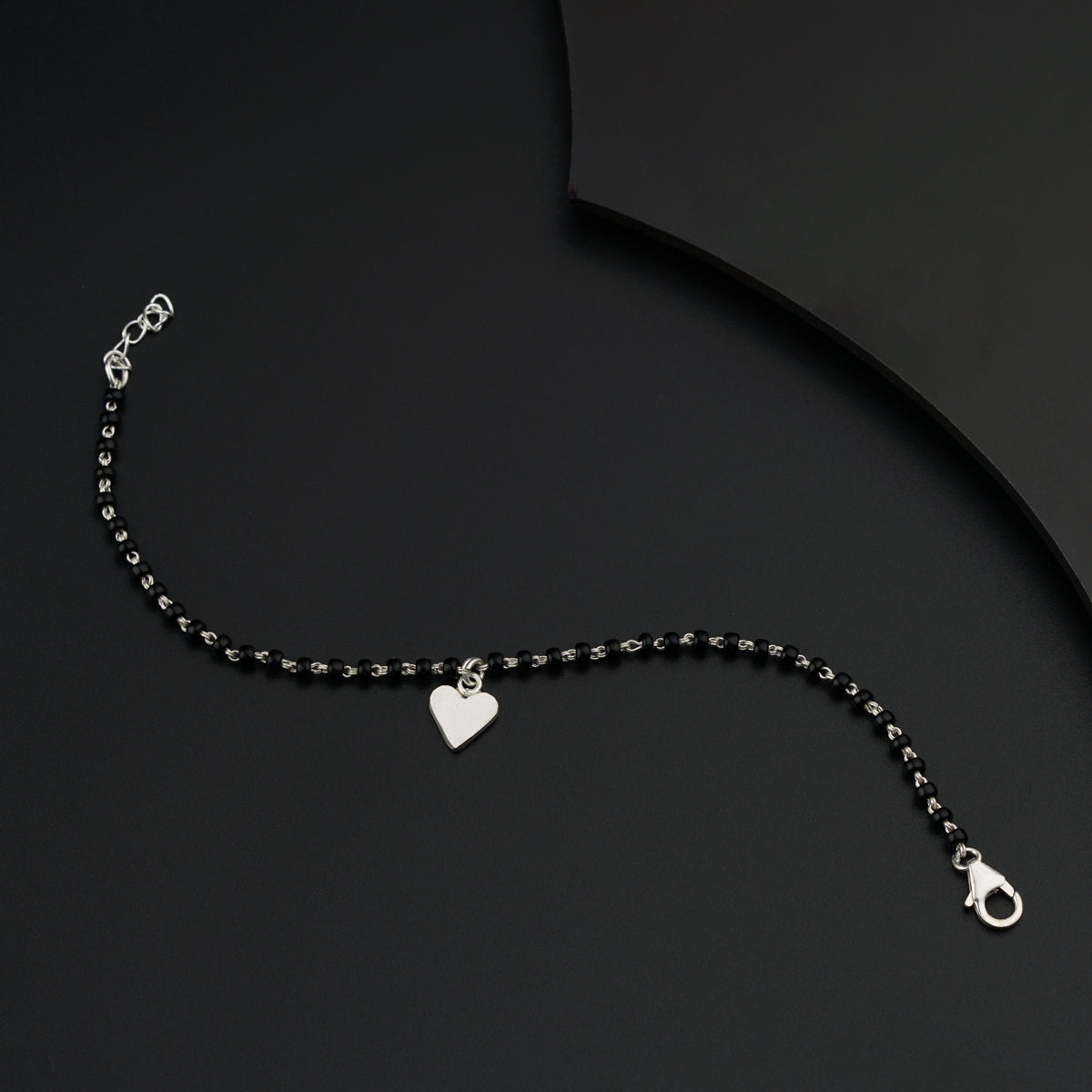 a black beaded necklace with a heart charm