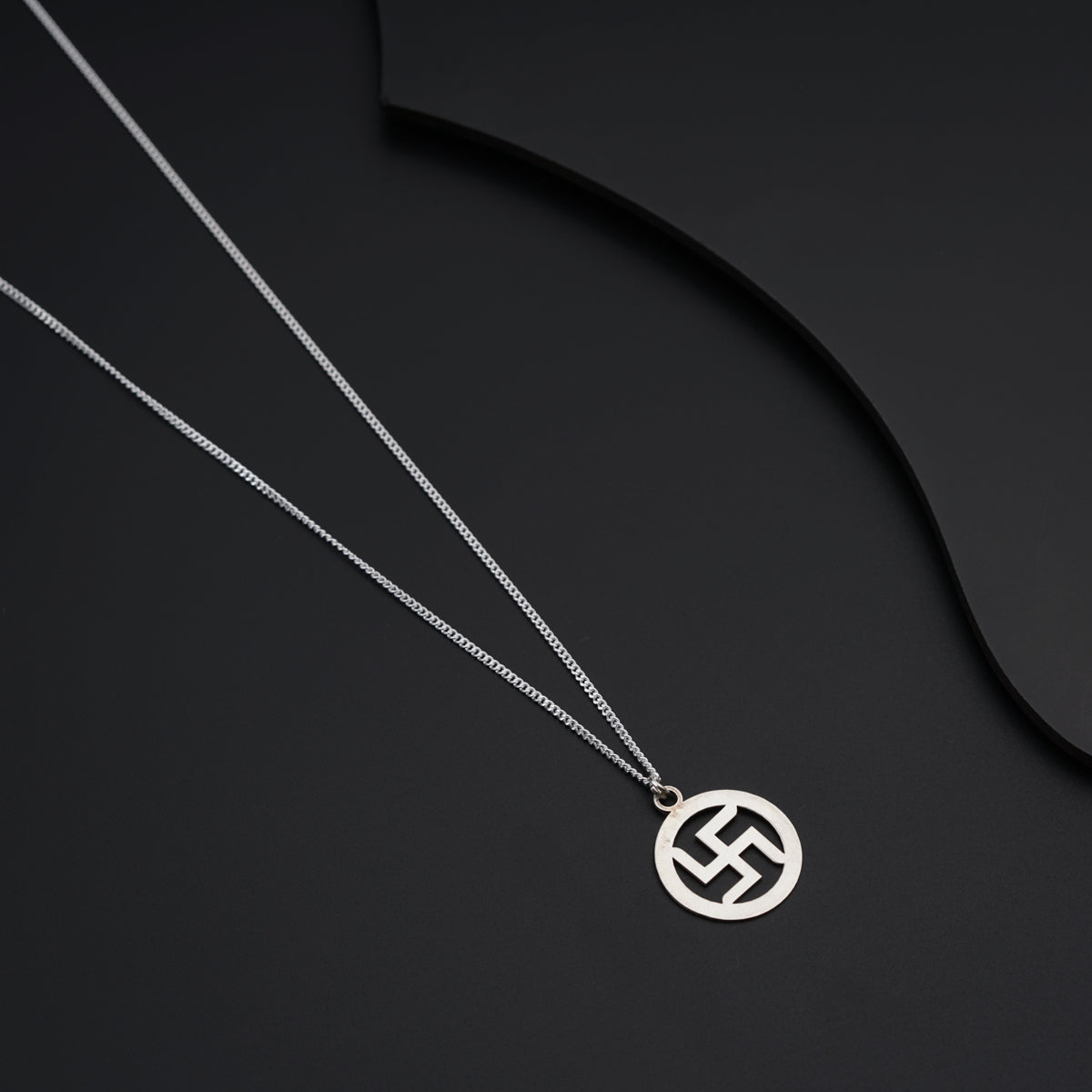 a silver necklace with a circular pendant on a black background