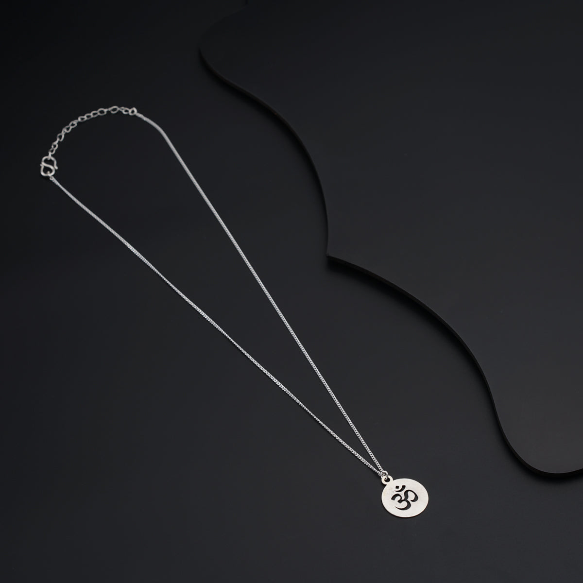 a necklace with a disc on a black background