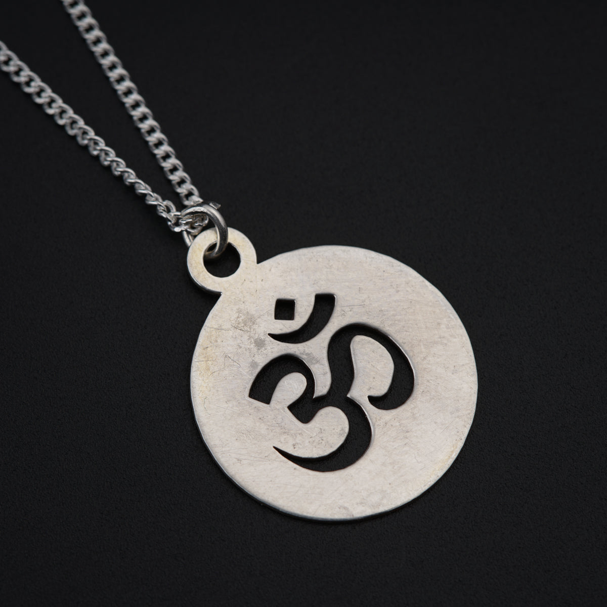 a silver necklace with a black omen symbol on it