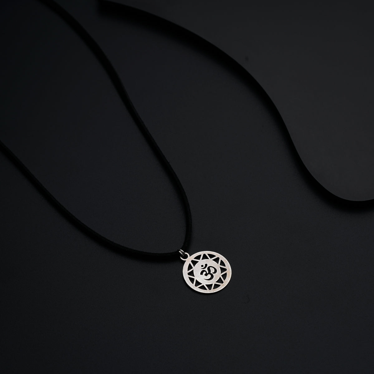 a necklace with a silver pendant on a black background