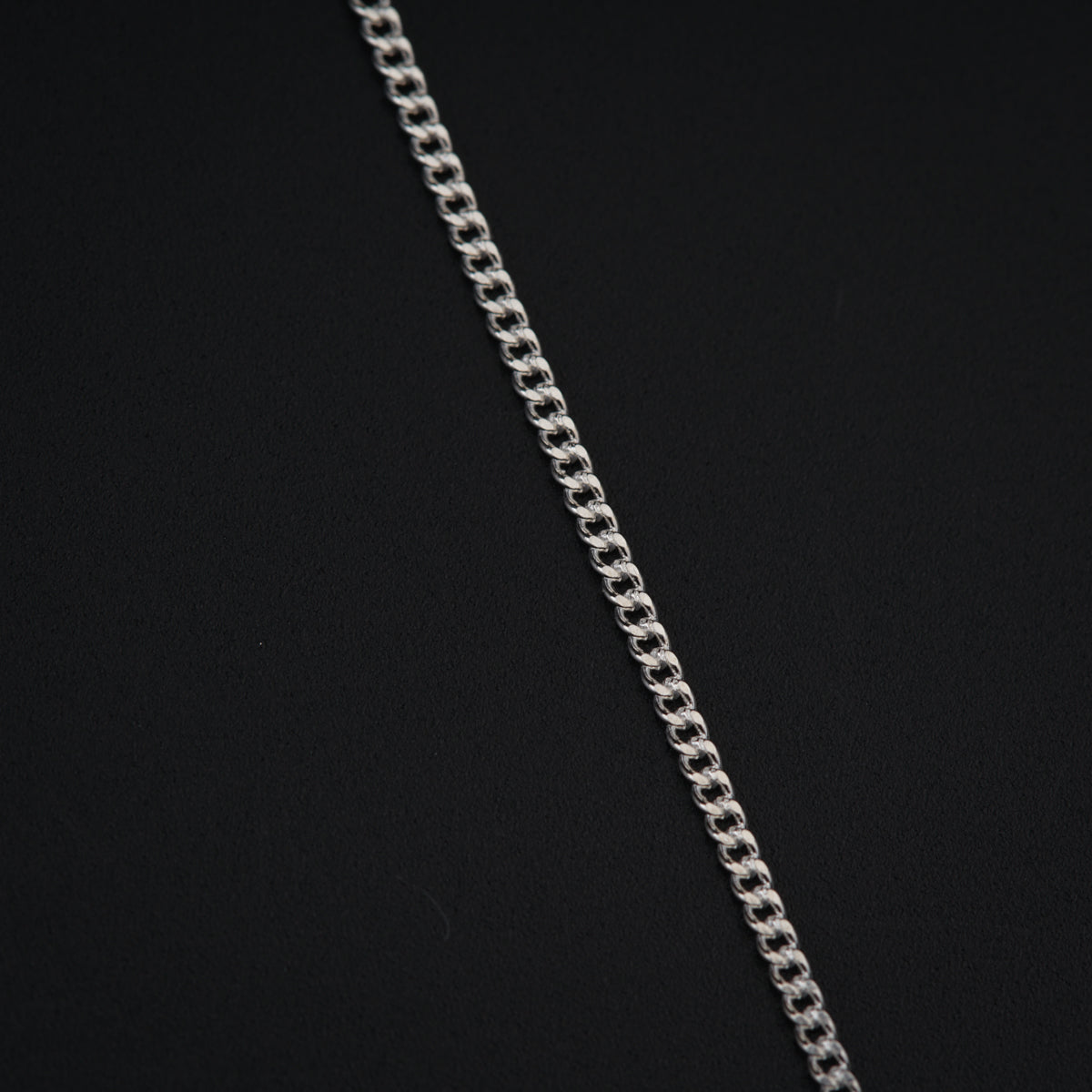 a silver chain is shown on a black surface