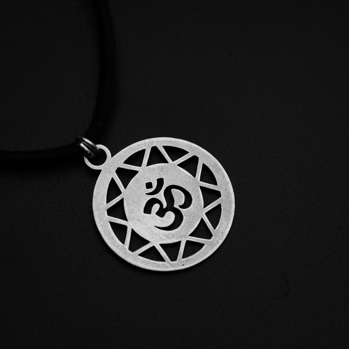 a silver pendant with an omen symbol on a black background