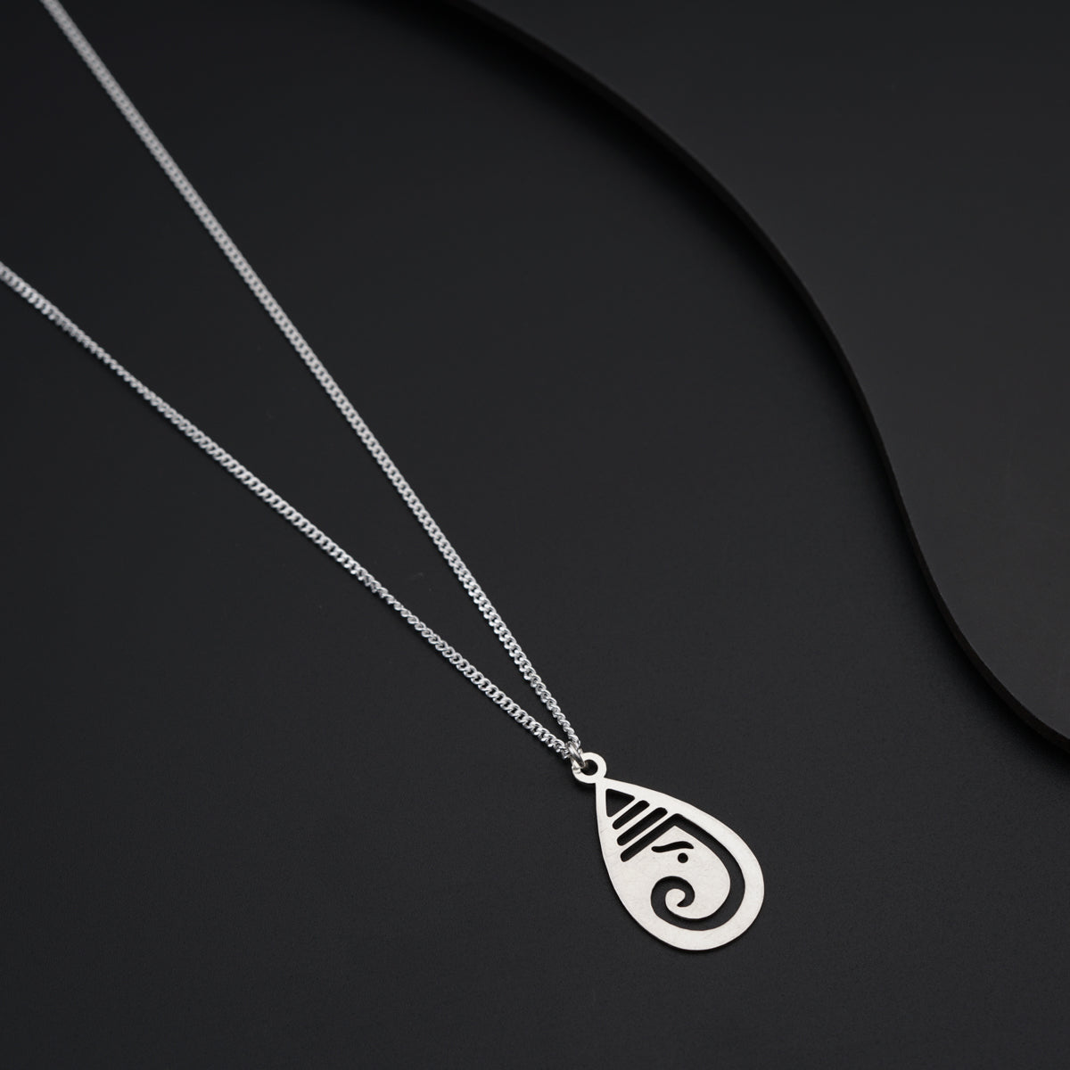 a silver necklace with a pendant on a black background