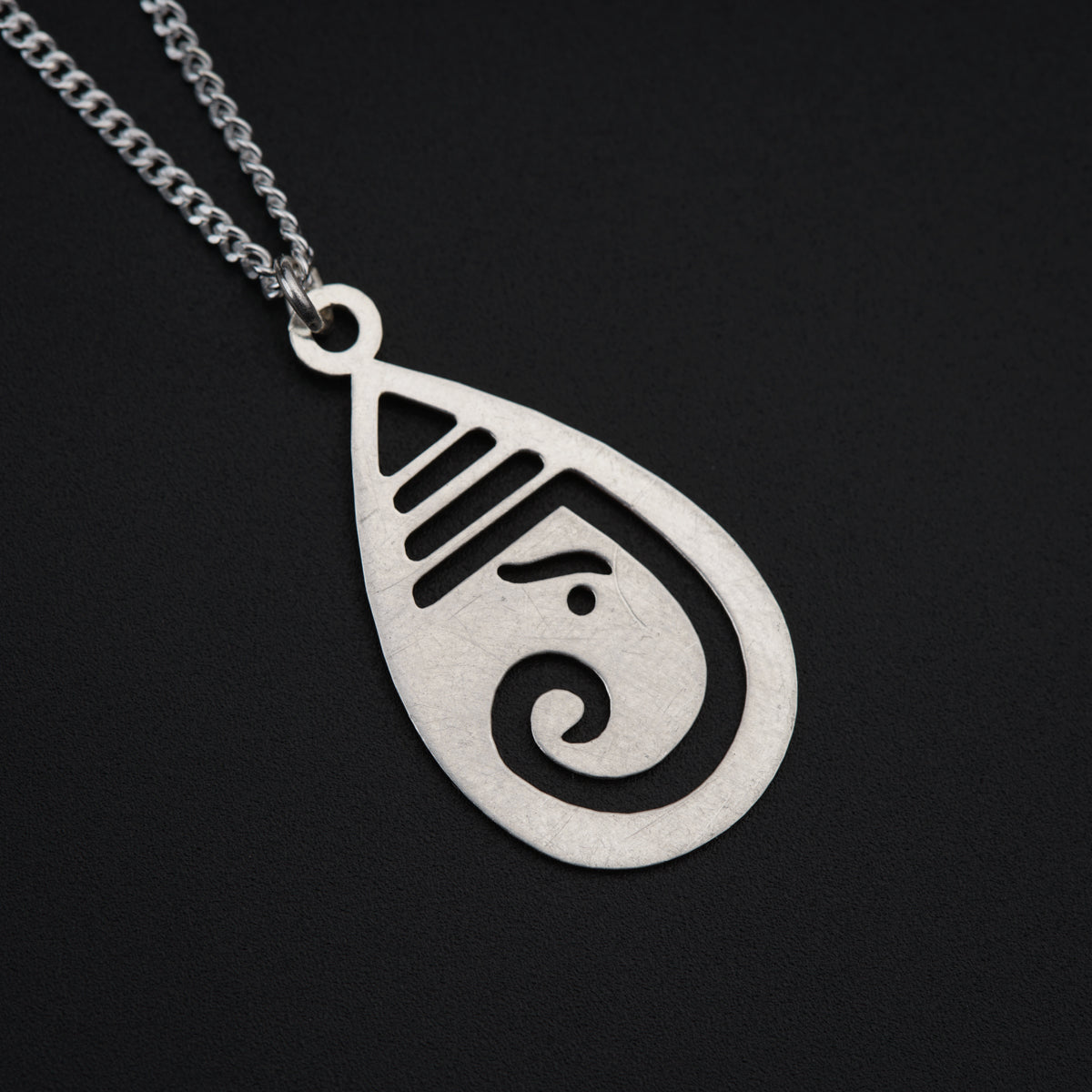 a silver necklace with a black and white design on it
