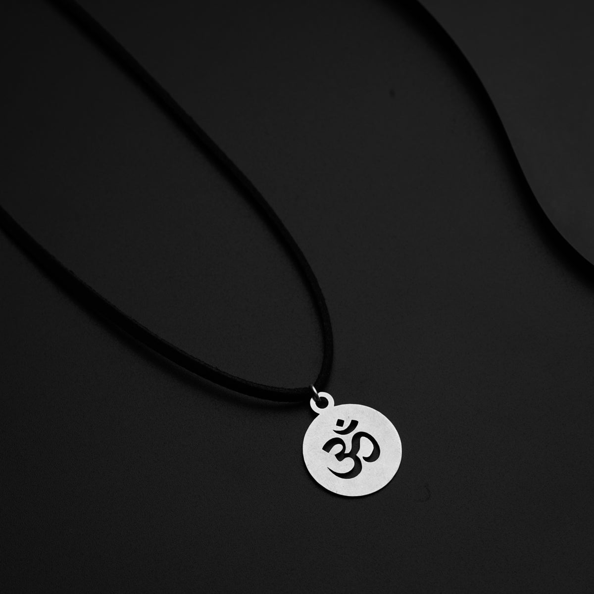 a necklace with an om symbol on a black background