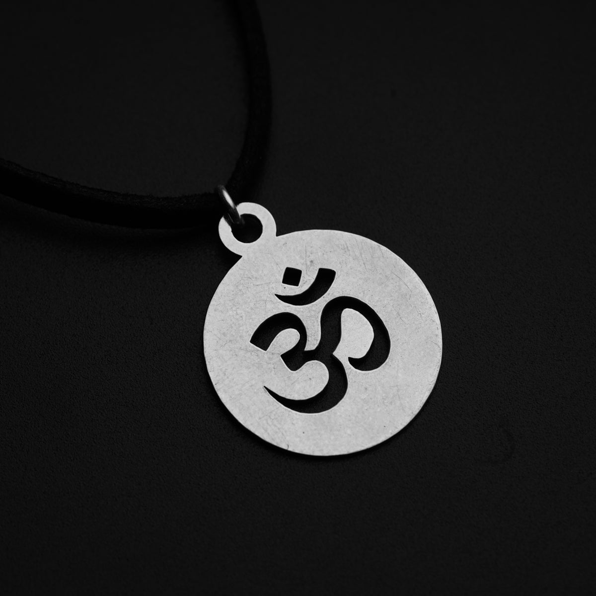 a silver pendant with an omen symbol on a black background