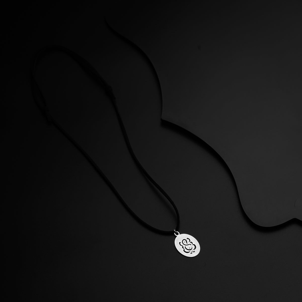 a black and white photo of a necklace on a black background