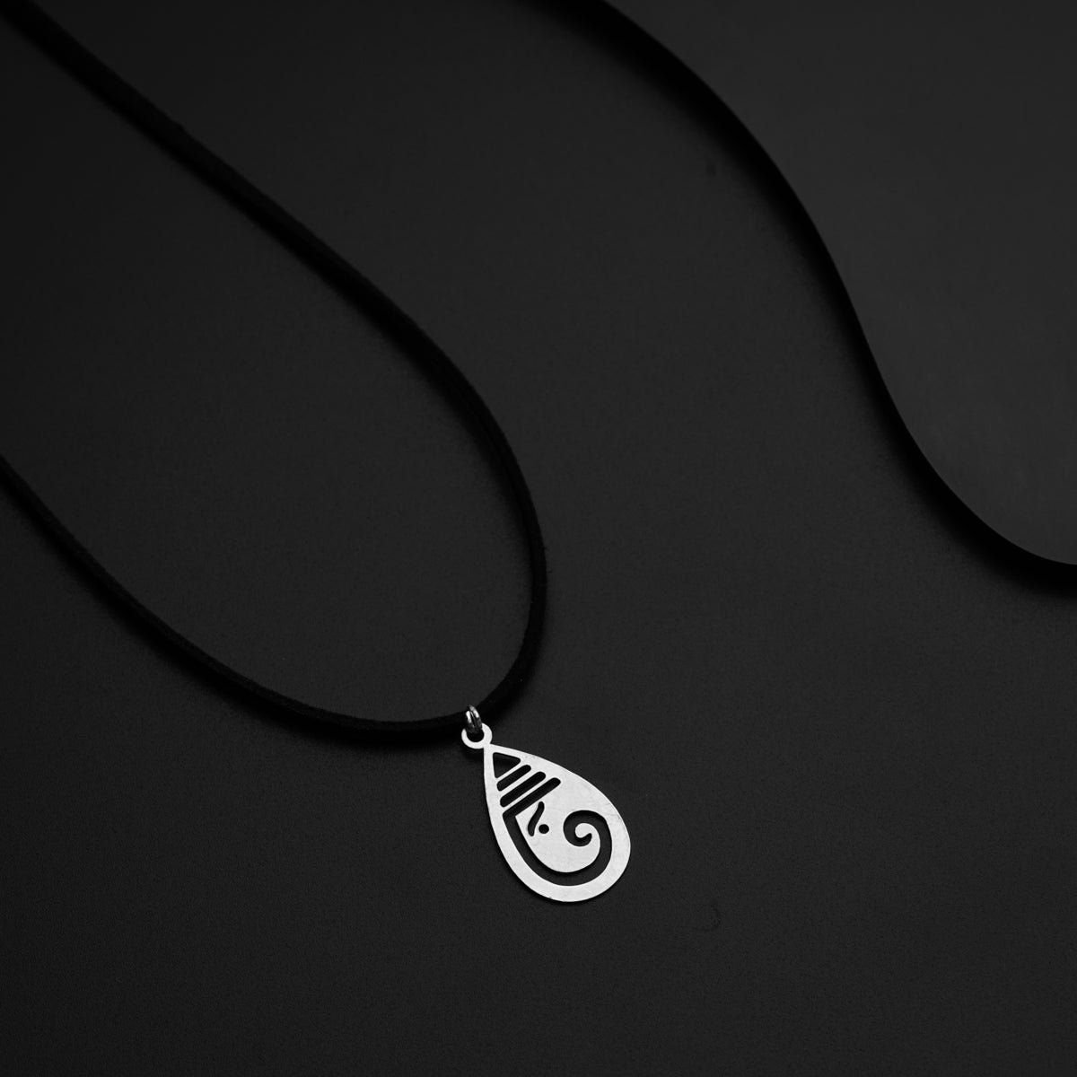 a black necklace with a silver pendant on a black background