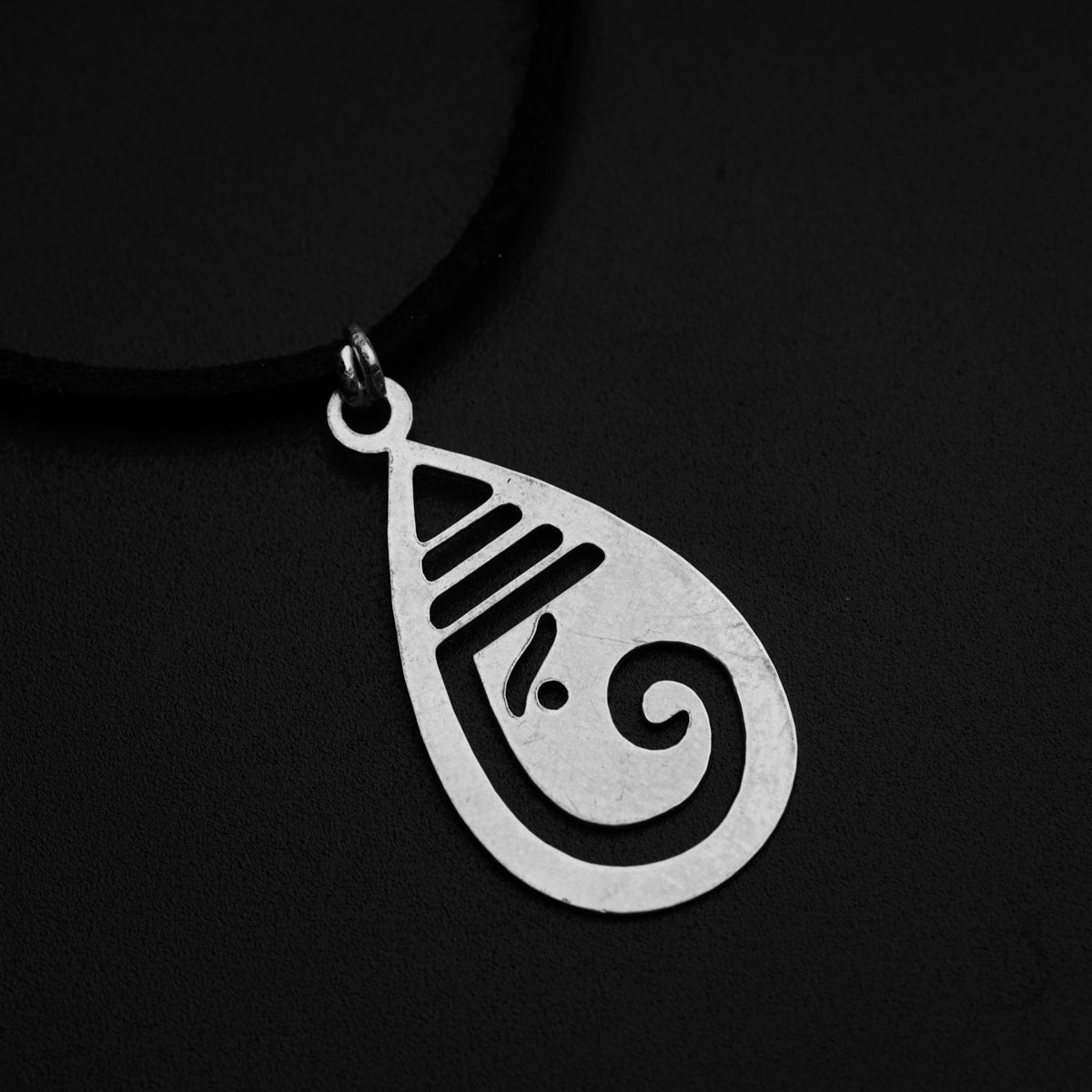 a silver pendant with a design on it