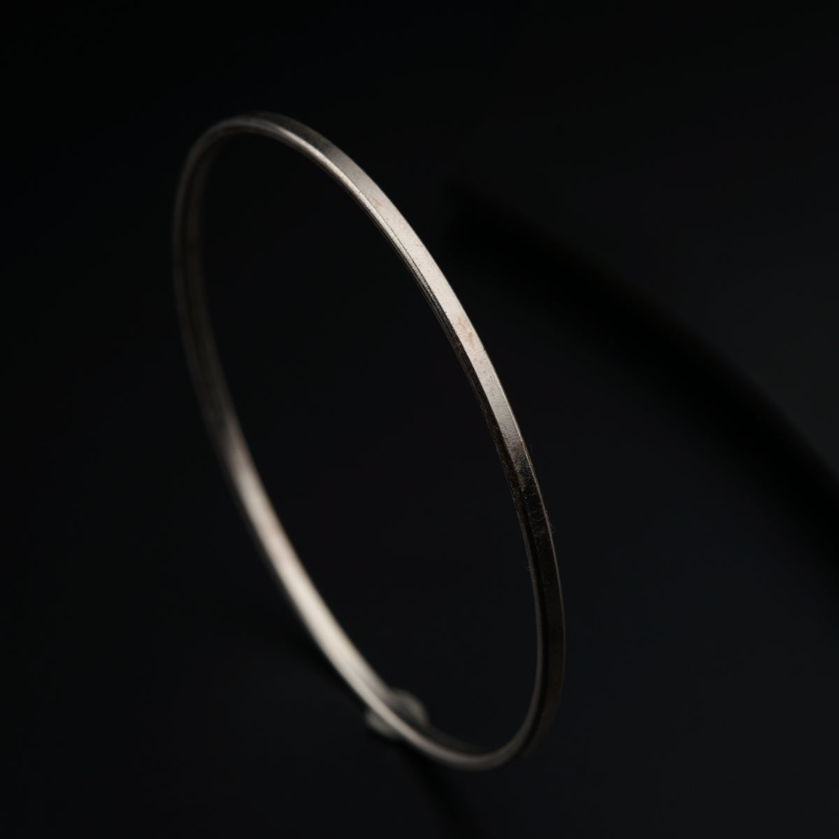 a thin silver bracelet on a black background