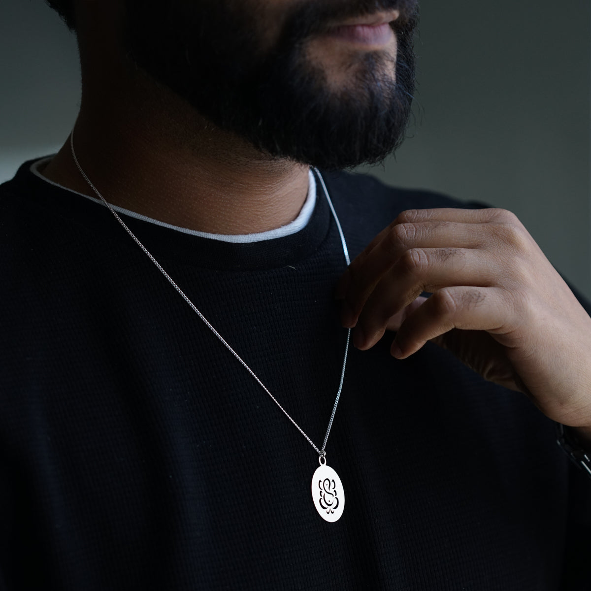 a man wearing a necklace with a monogrammed disc on it