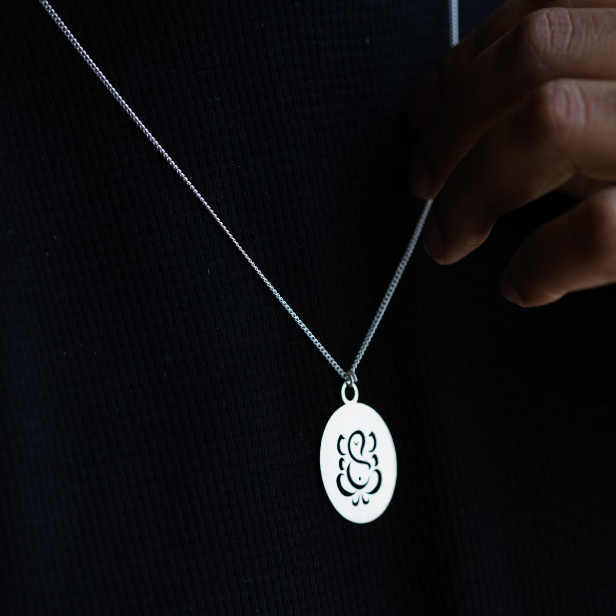 a person wearing a silver necklace with a white omen symbol on it