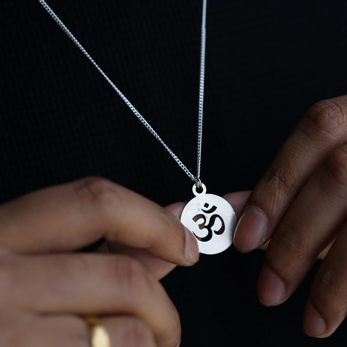 a person holding a necklace with an om symbol on it