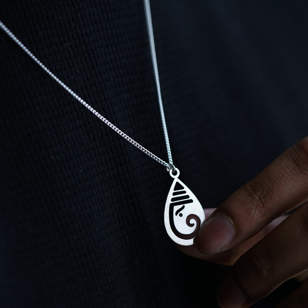 a person wearing a necklace with a pendant on it