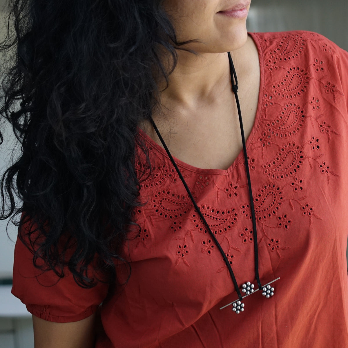 a woman wearing a red shirt and a black necklace