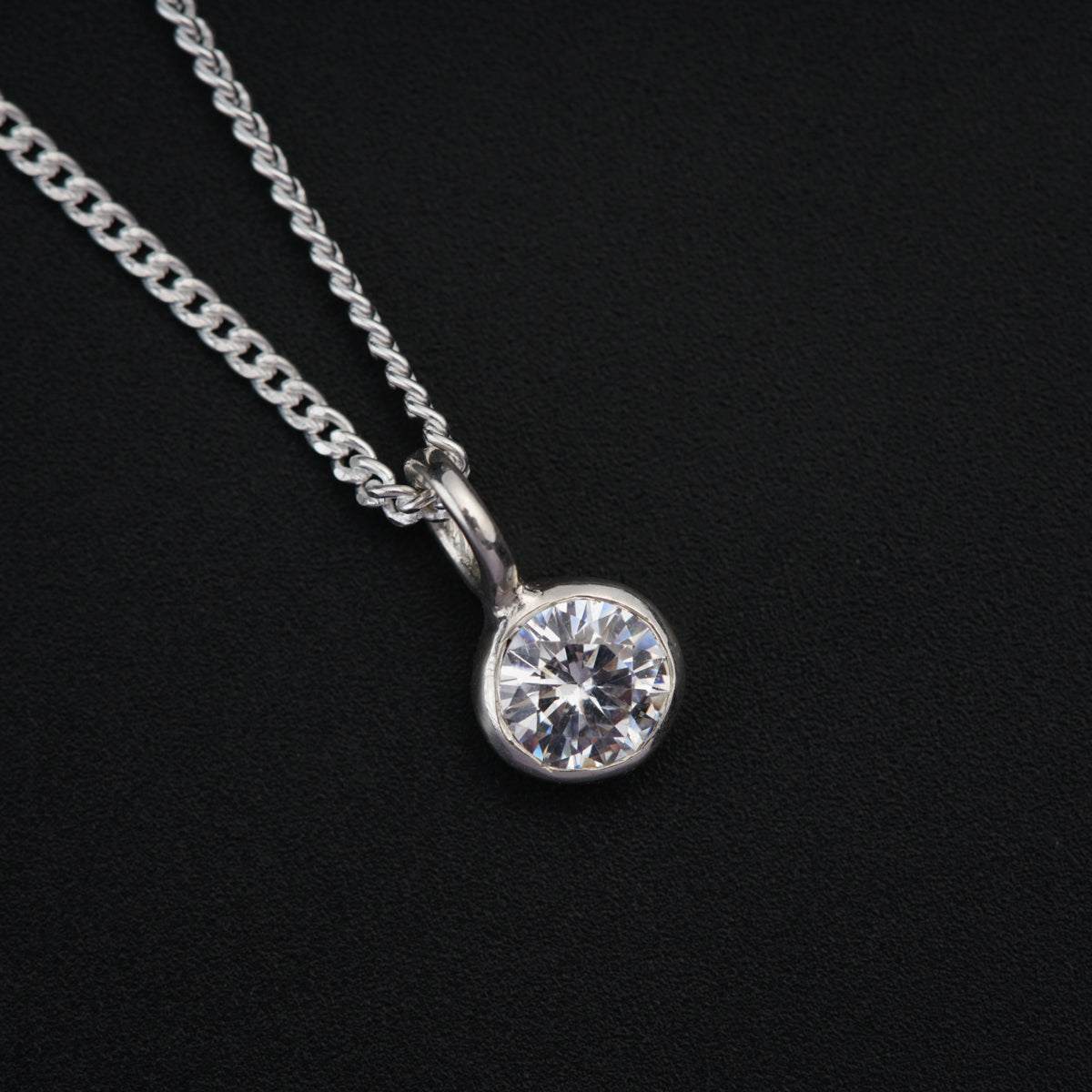 a diamond pendant on a chain on a black background