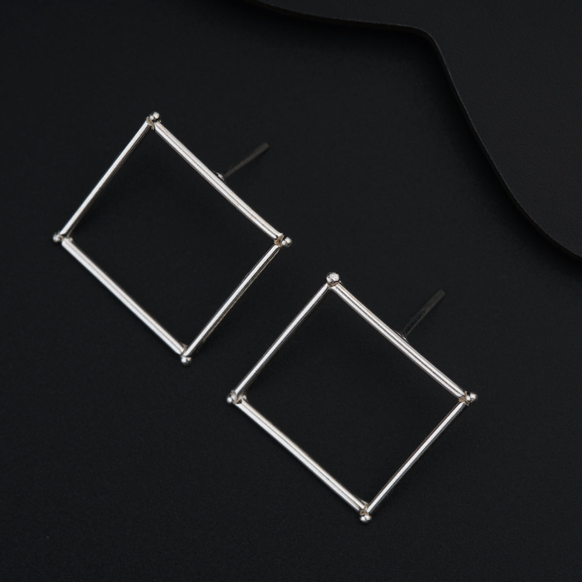 a pair of square earrings on a black surface
