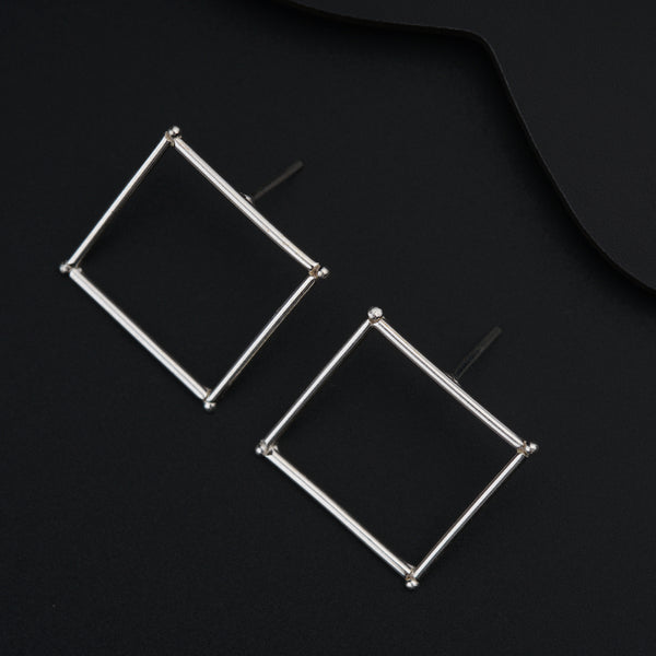 a pair of square earrings on a black surface
