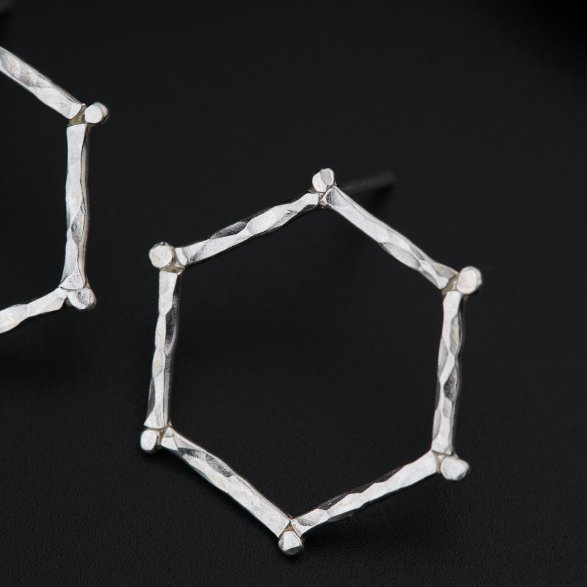 a pair of silver earrings on a black surface