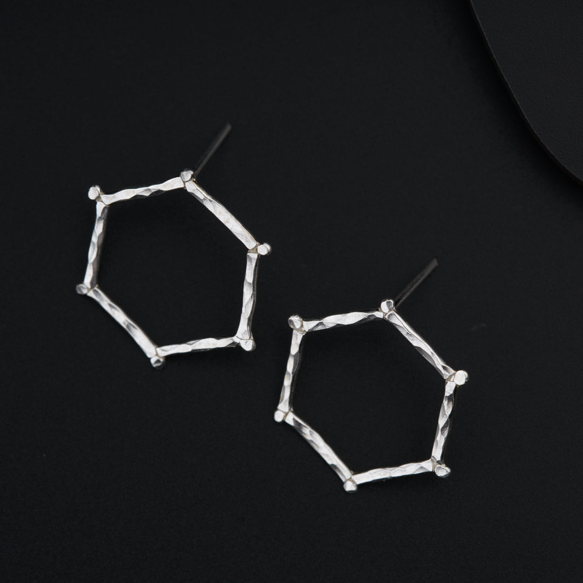 a pair of silver earrings on a black surface