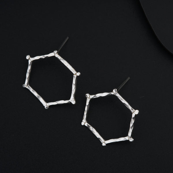 a pair of silver earrings on a black surface