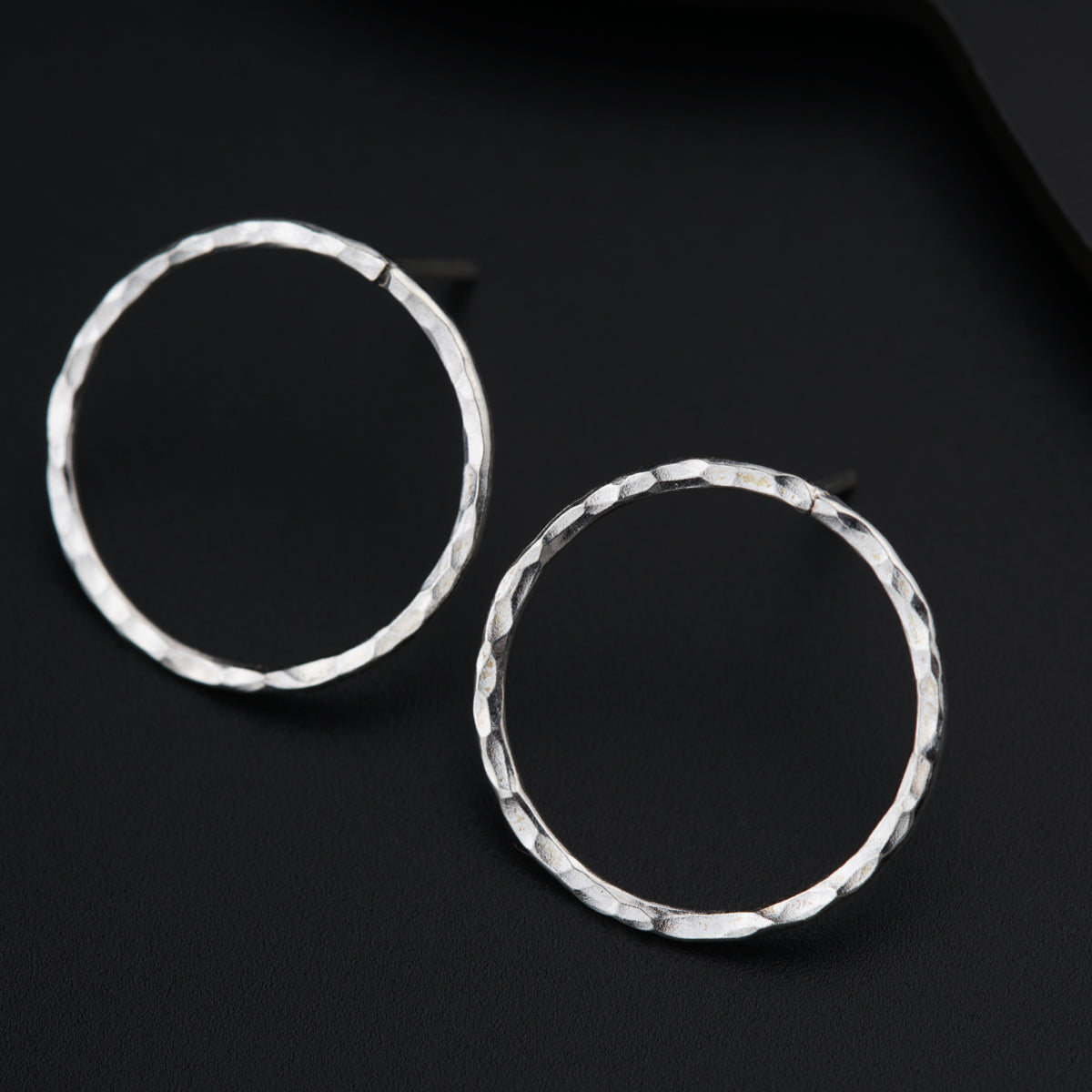a pair of silver hoop earrings on a black surface