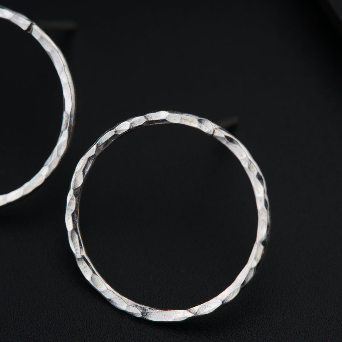 a pair of silver hoop earrings on a black surface