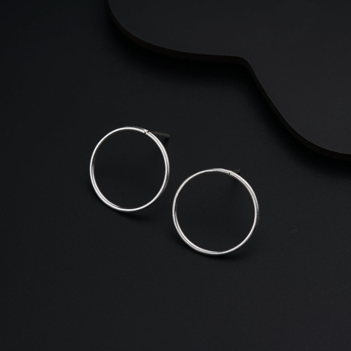a pair of silver hoop earrings on a black background