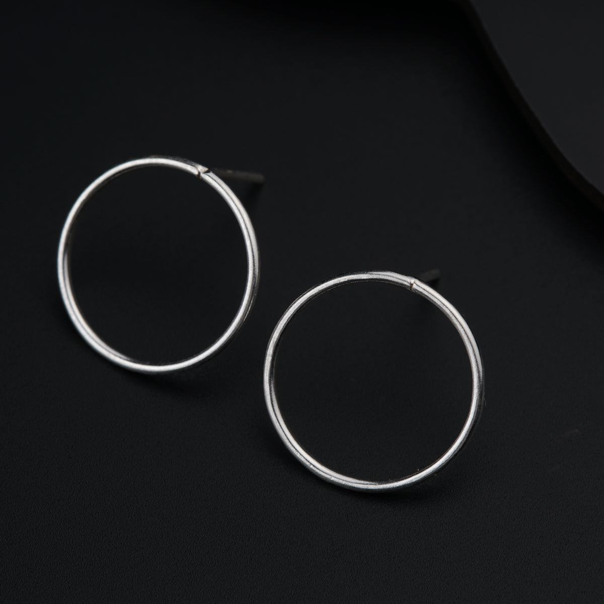 a pair of silver hoop earrings on a black surface