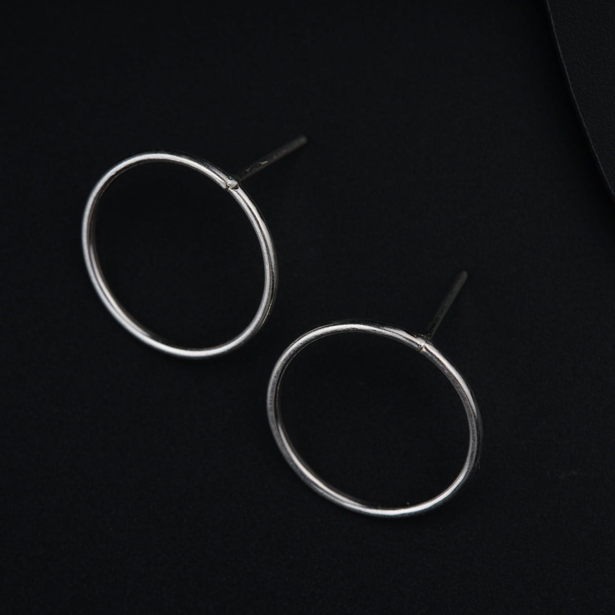a pair of silver hoop earrings on a black background