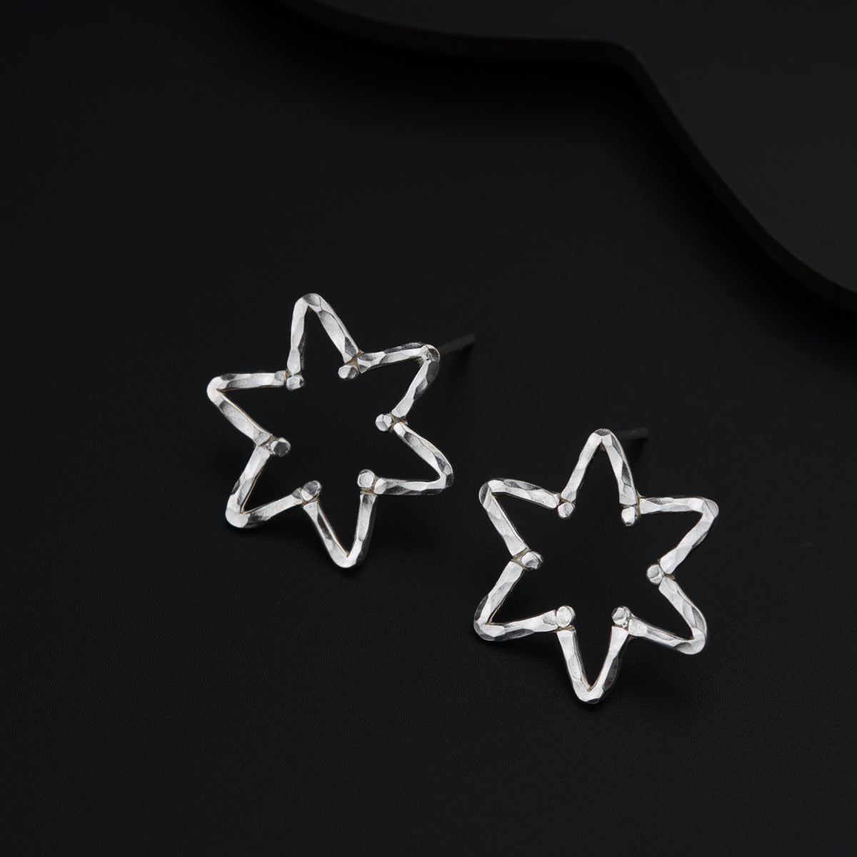 a pair of star shaped earrings sitting on top of a black surface