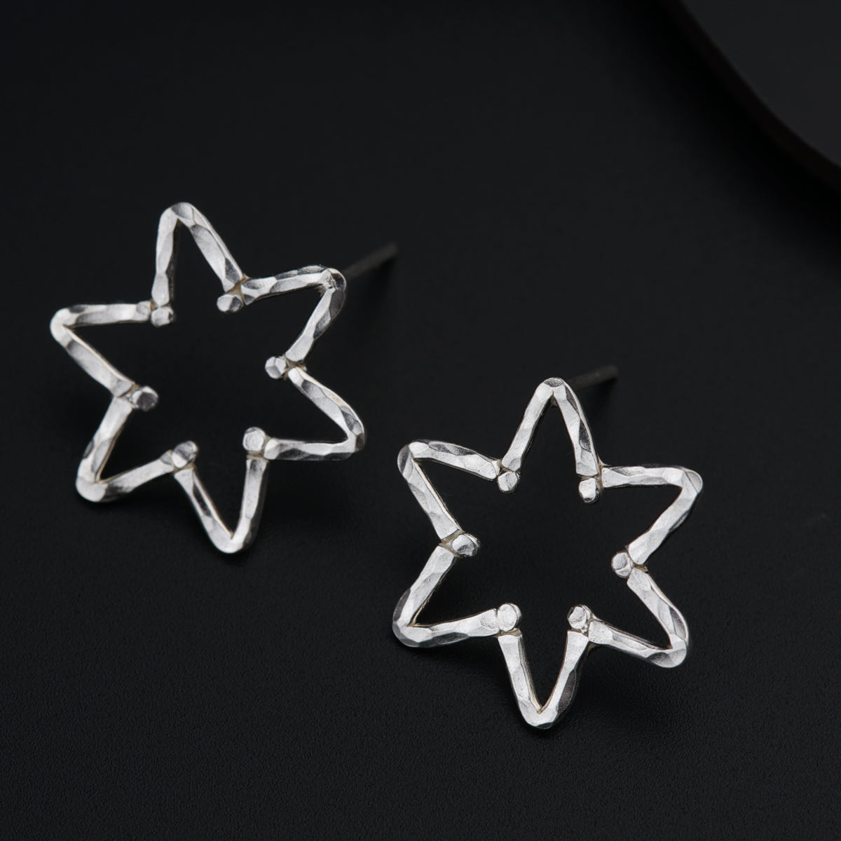 a pair of star shaped earrings sitting on top of a table